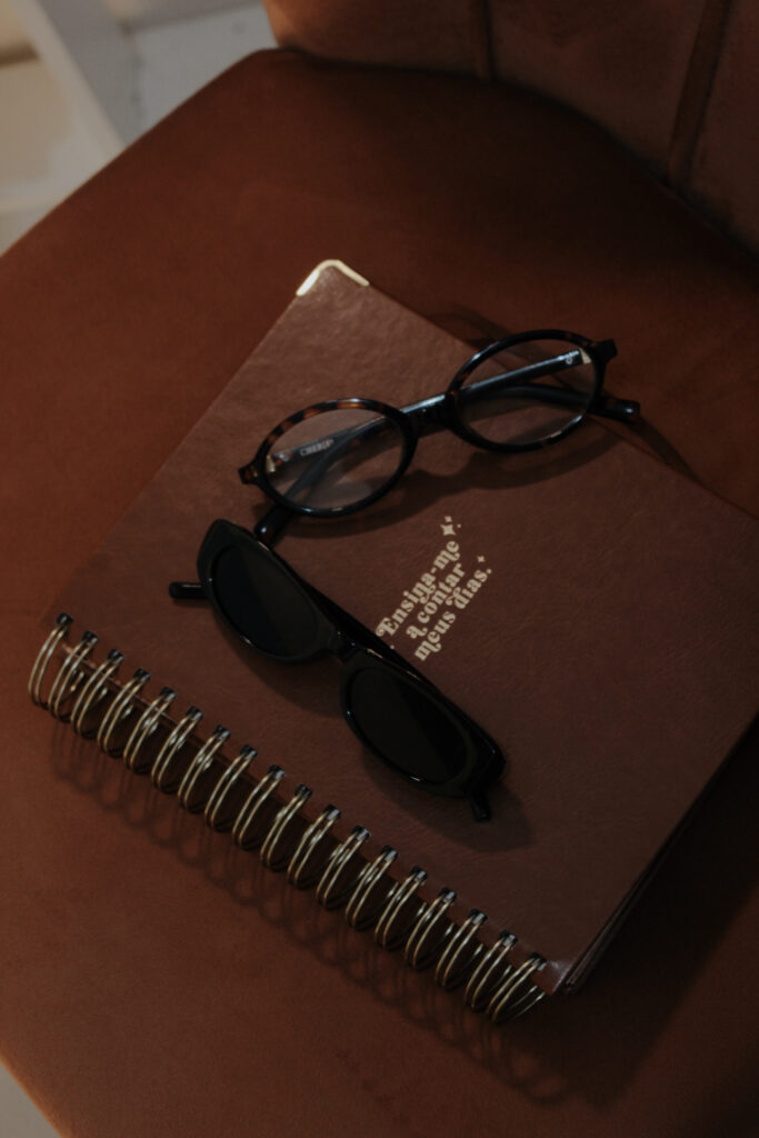 Óculos de grau de armação preta sobre um caderno marrom com espiral
